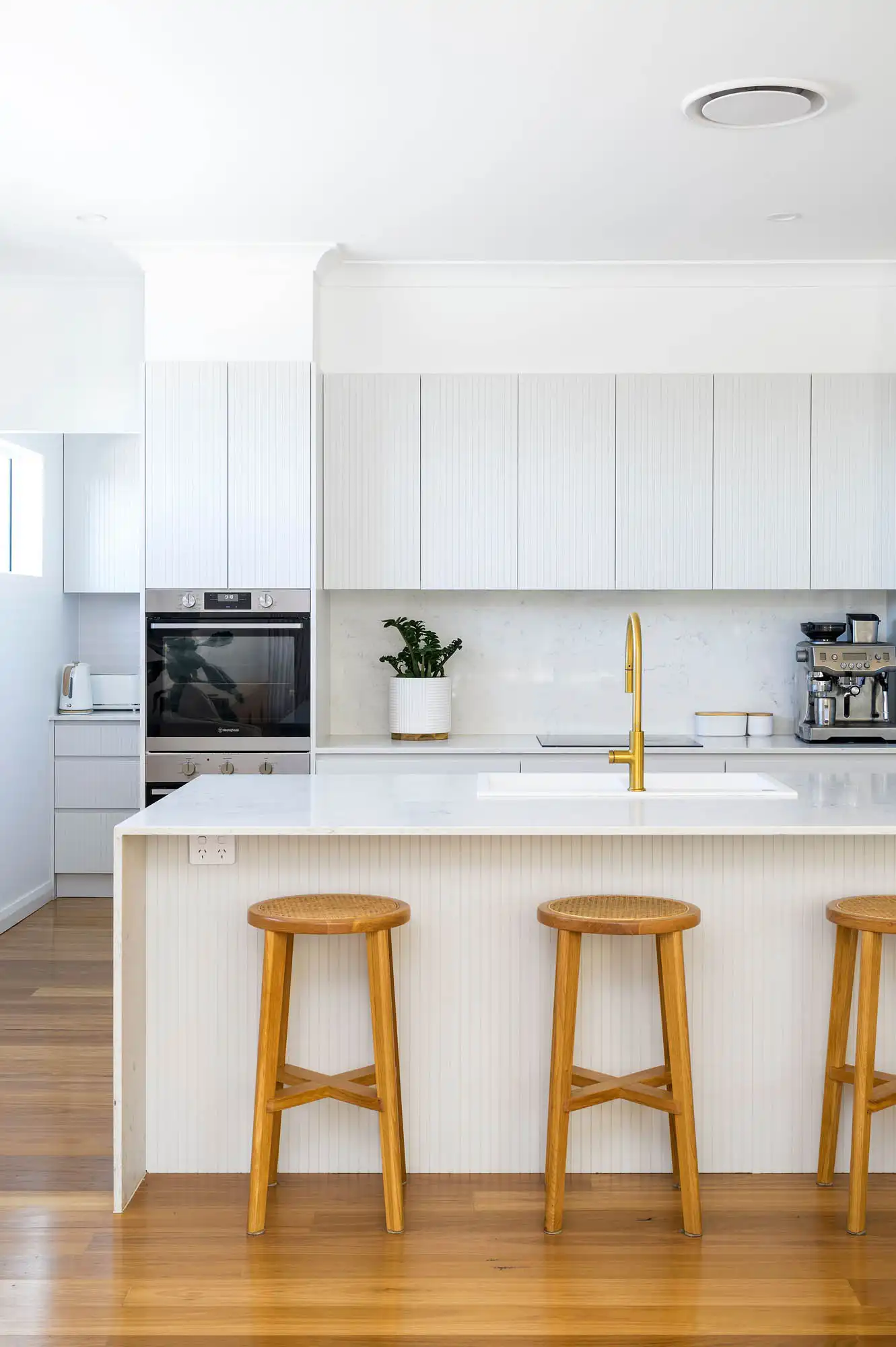 white modern kitchen with island bench and timber stools